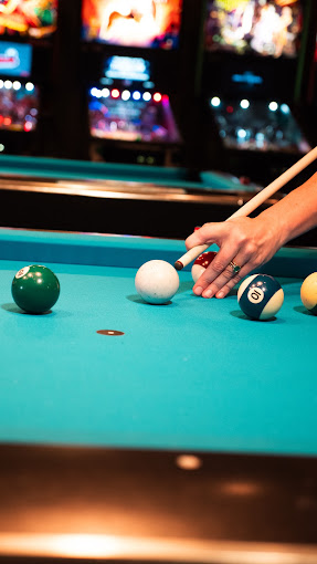 Bridge hand lining up a shot over teal cloth on a coin-op table