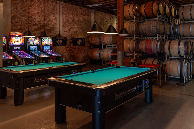Two 7-foot coin-op pool tables with clear walking space beside pinball machines at Beachwood Blendery