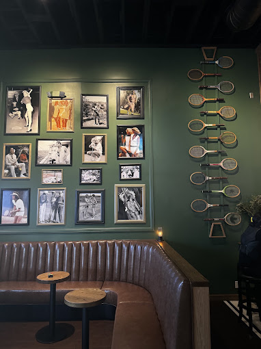 Leather banquette and vintage tennis racket wall inside The Palm & The Pine